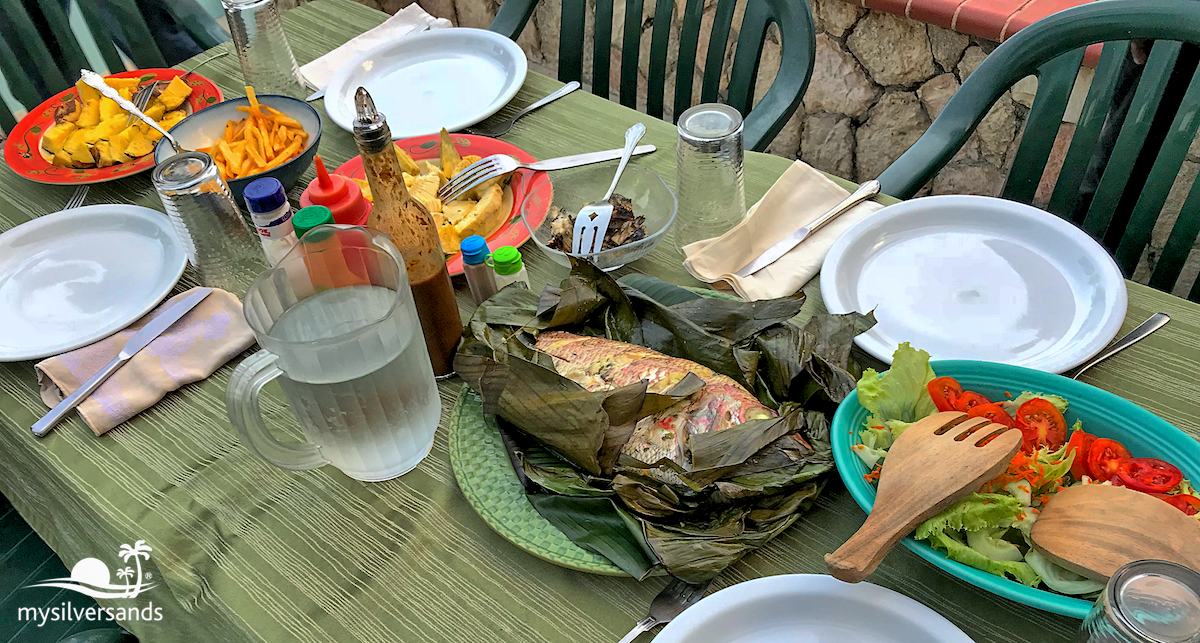 table spread with steam fish, breadfruit, sweet potato and salad