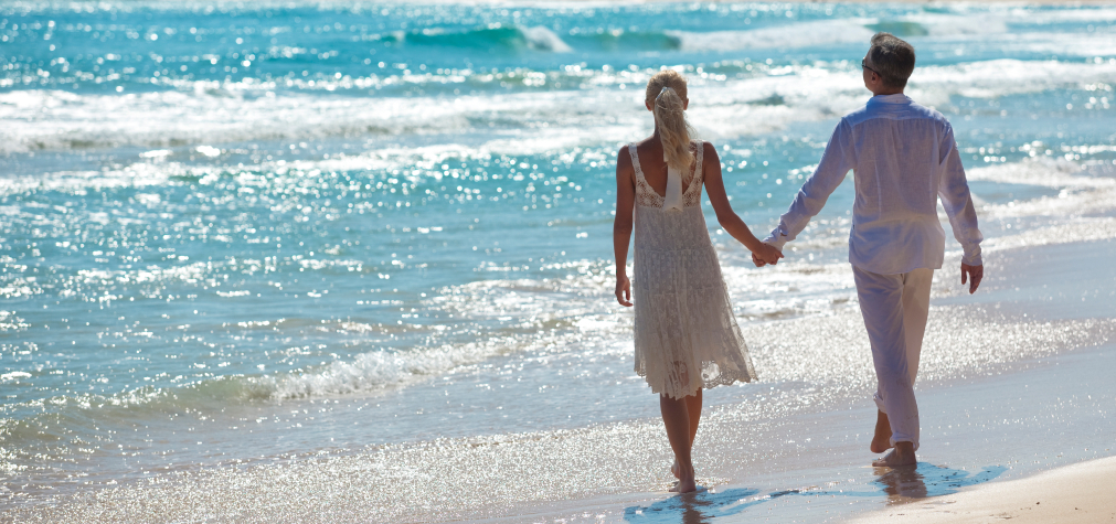 bride and groom holding hands on the beach after destination wedding