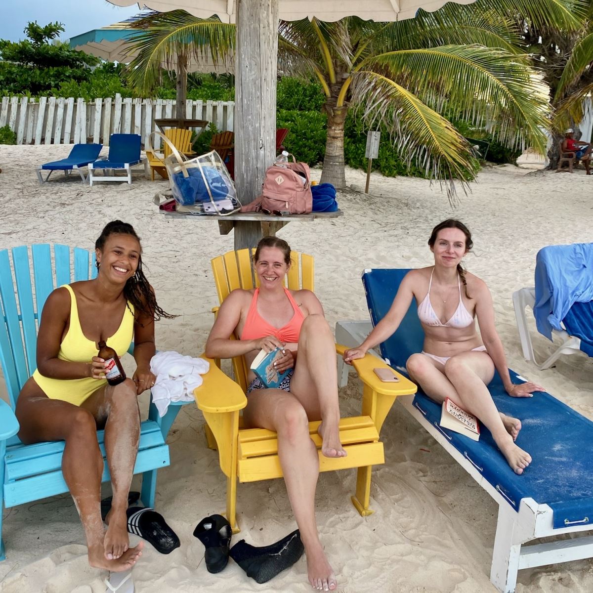 3 women sitting on beach under cabana