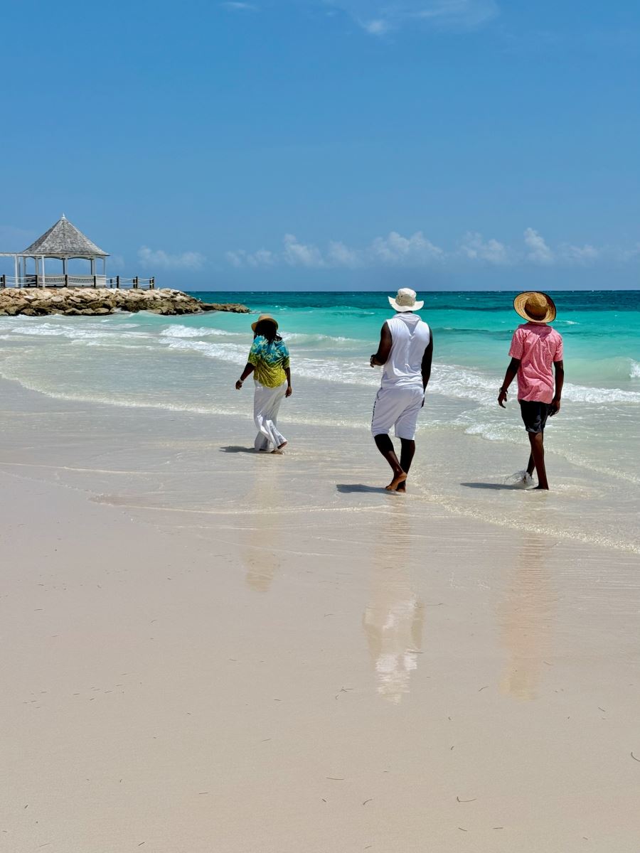 3 people walking on the beach towards the jetty and gazebo
