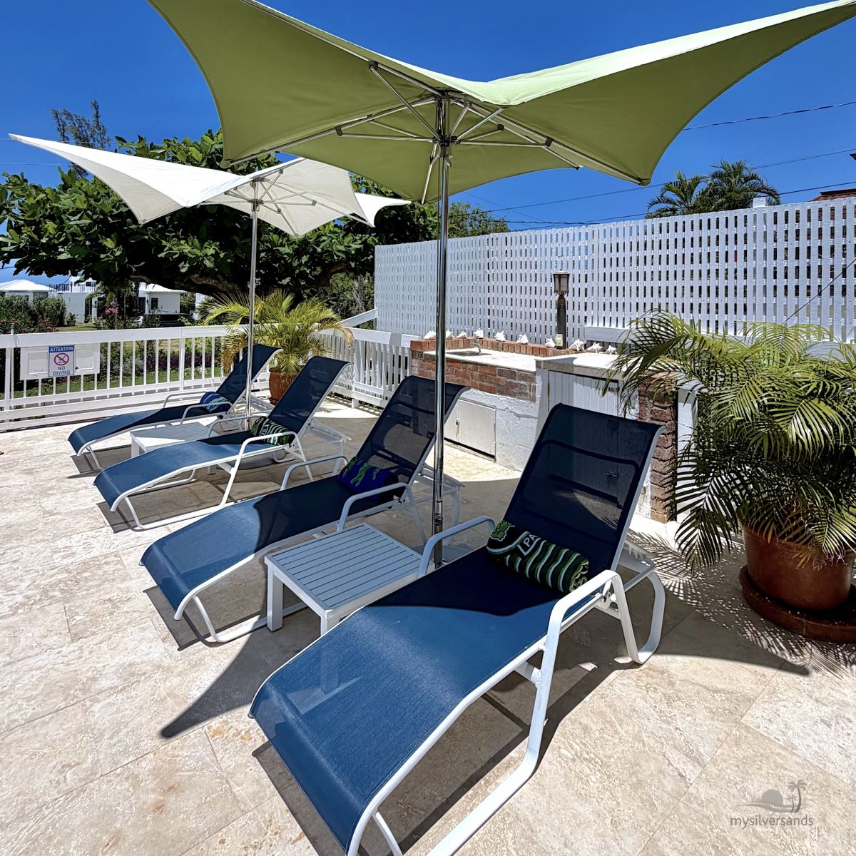 lounge chairs under umbrellas poolside