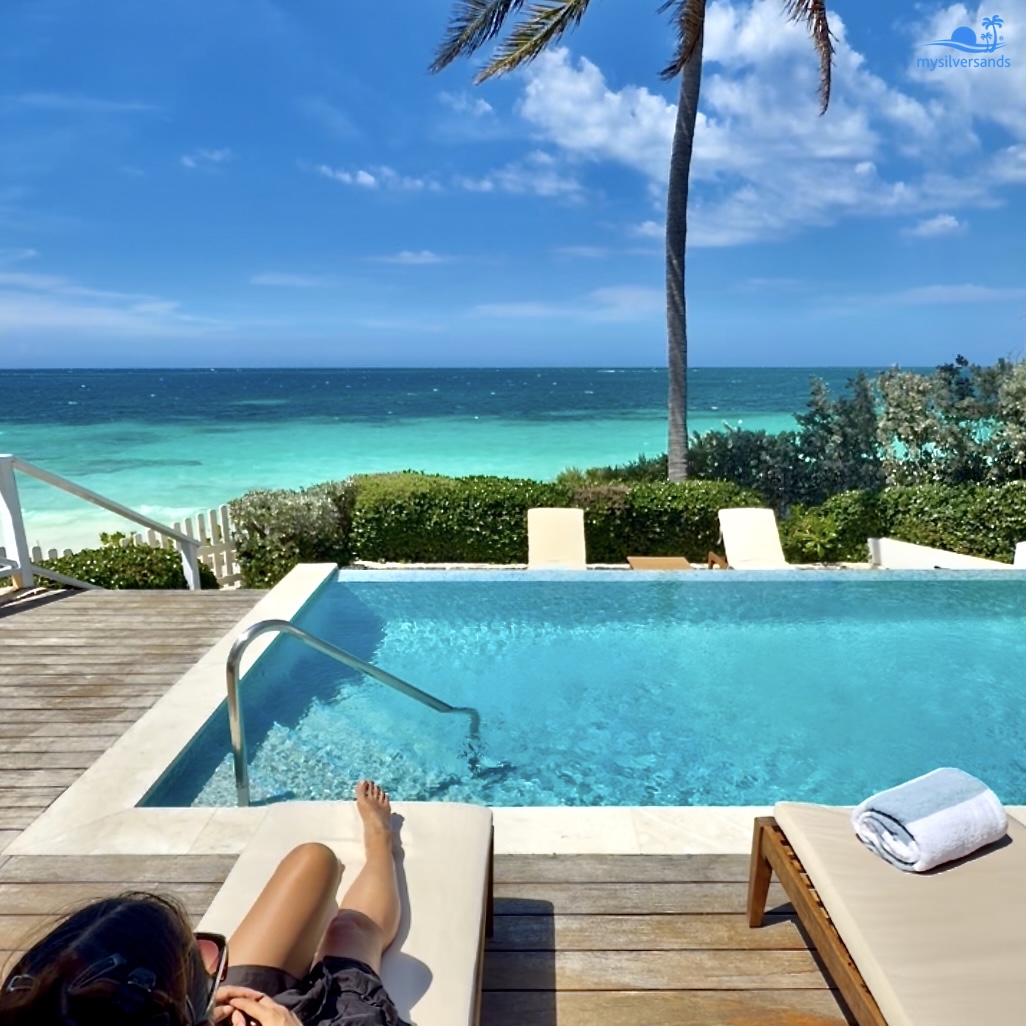 woman on deck on lounger with pool and sea view