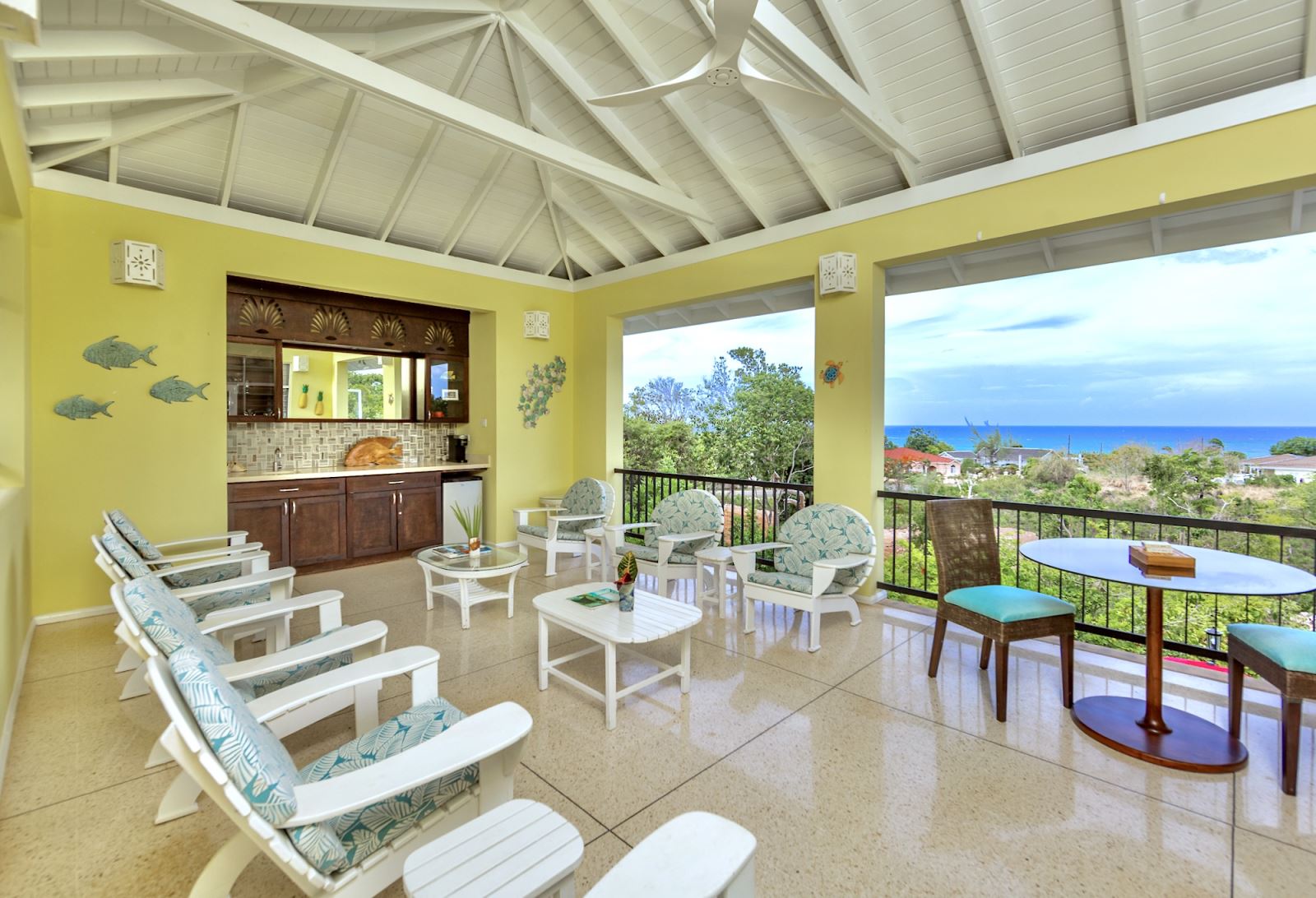Breezy upper verandah with bar, comfy seating, and Caribbean Sea views.