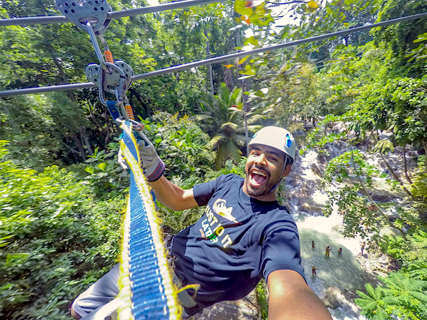 closeup of man ziplining over falls 