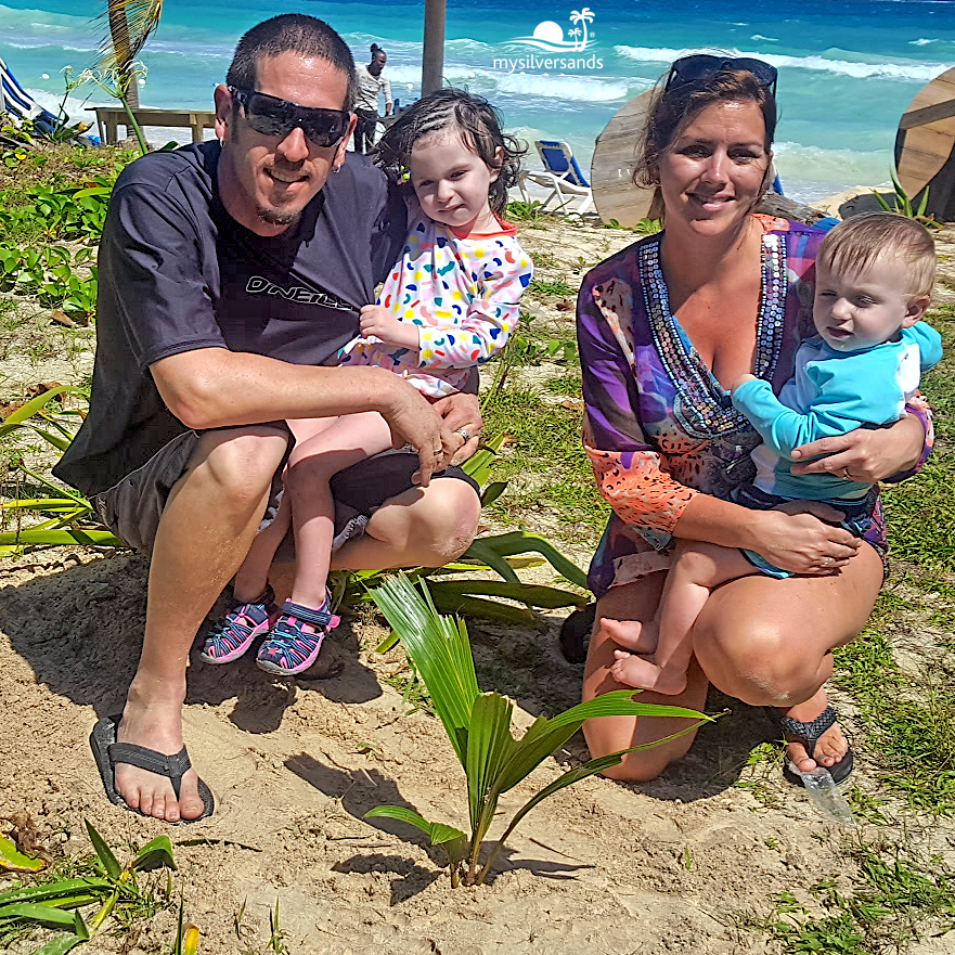 family smiling with their tree, planted.