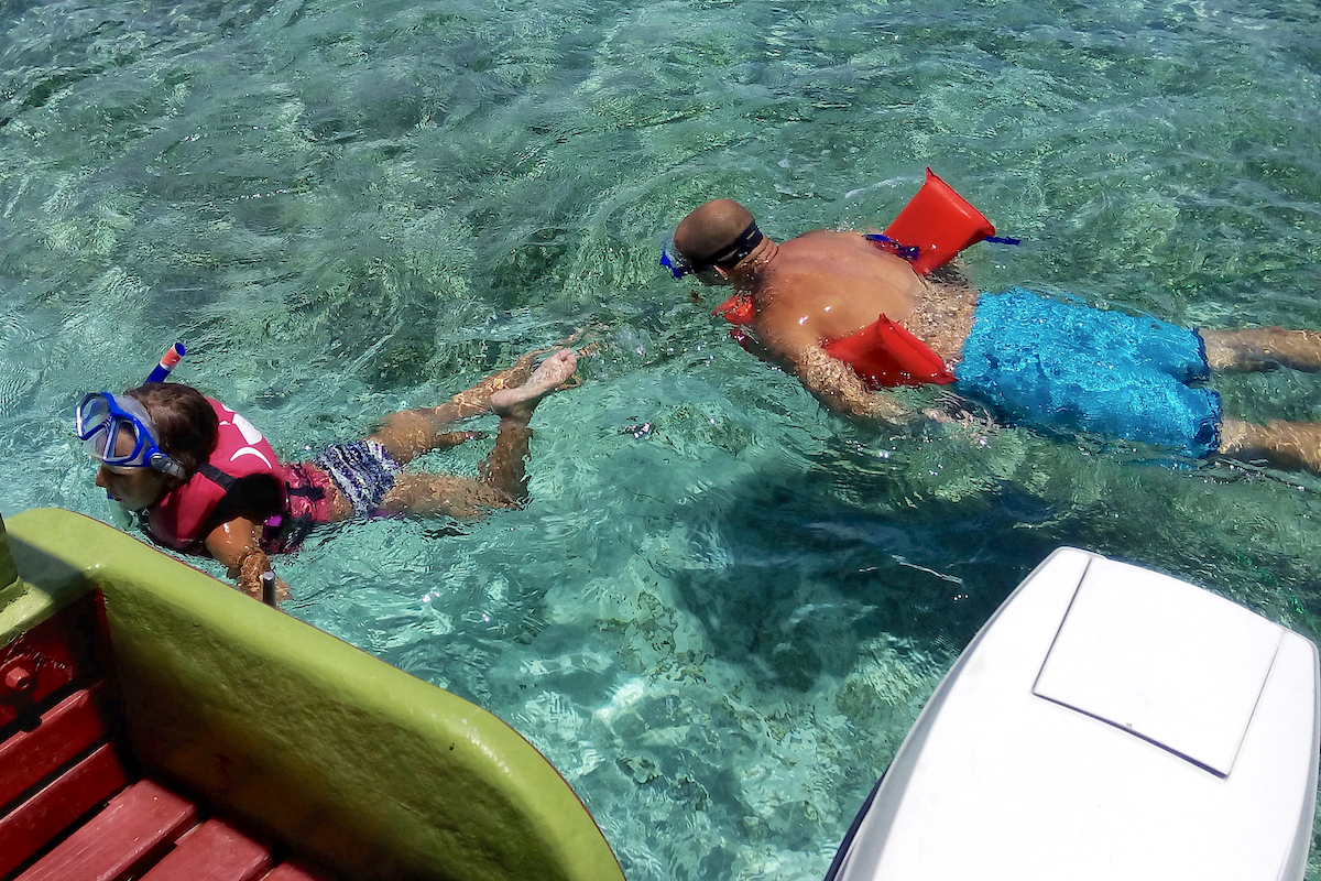 man and child snorkeling near the boat