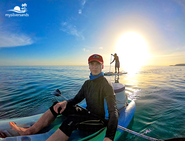 randy sitting in kayak with paddle boarders in background