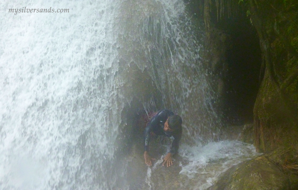 climbing out of the hole in the rock under the waterfall