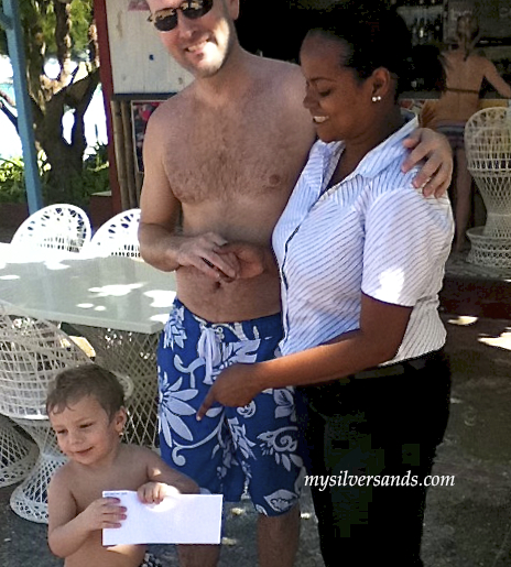 davia presents gift certificate to man and boy on patio at silver sands jamaica