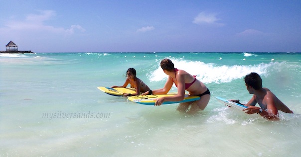 3 teenagers setting off on their bodyboards at silversands jamaica