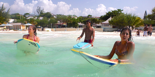 3 teens walking out from silver sands beach with their bodyboards