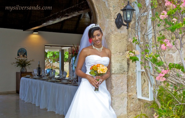bride at the entrance arch to rum jetty with the wedding dinner table